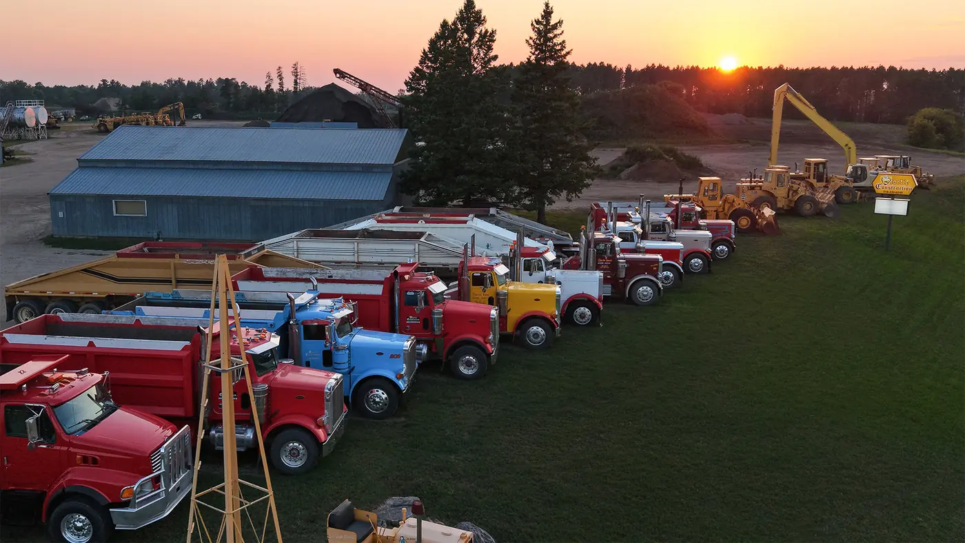 Storlie Construction's yard at sunset with the truck and loader fleet lined up